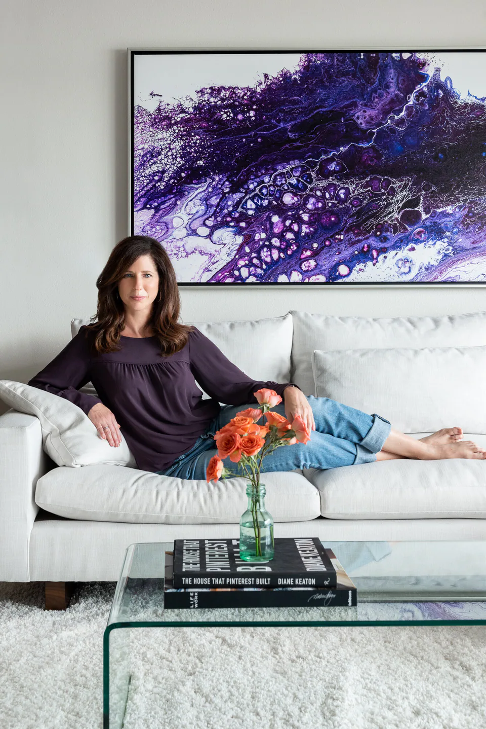Michelle Jennings in a Gulf Beaches condominium living room she designed, beneath a violet abstract painting