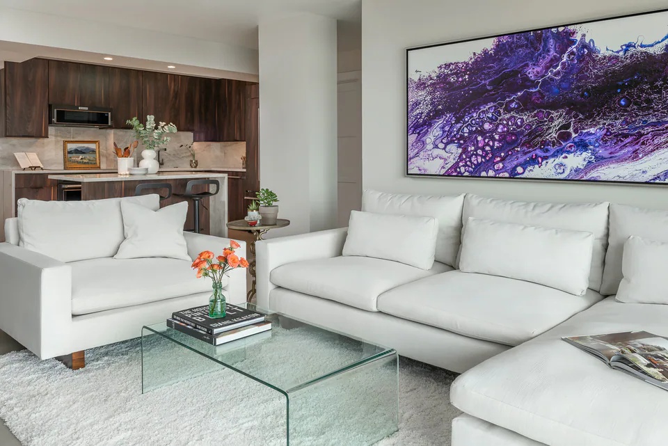 Living room with a white sectional and a glass coffee table at Gulf Beaches Condo, interior design by MJ Designs